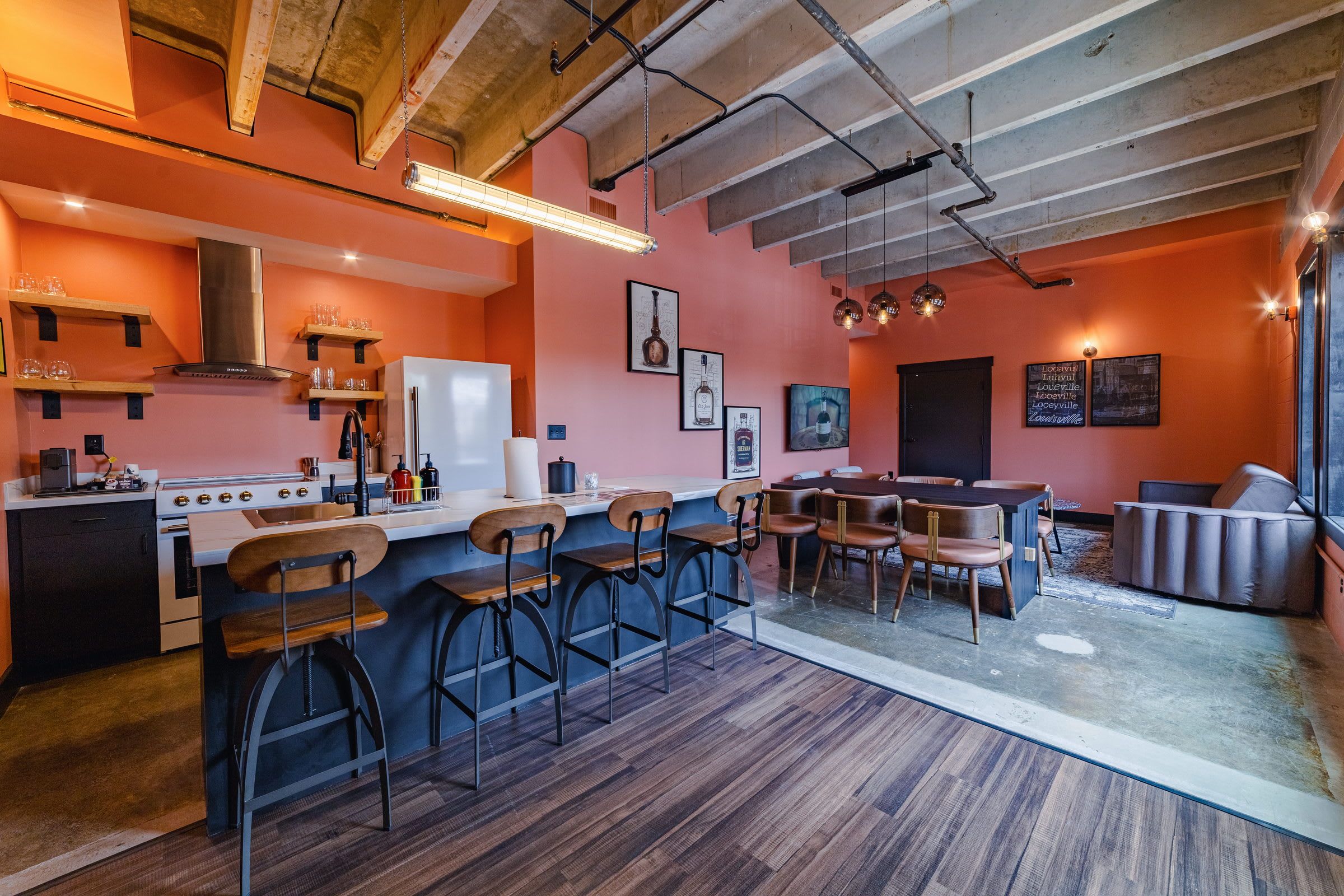A modern kitchen with bar stools, a dining area with a table and chairs, and a bar area with a sofa.