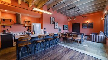 A modern kitchen with bar stools, a dining area with a table and chairs, and a bar area with a sofa.