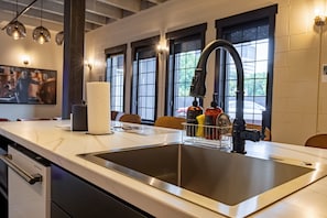A modern kitchen with a stainless steel sink, a faucet, and a dish soap dispenser.