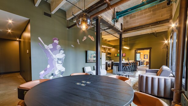 A modern interior with a round table, chairs, and a mural of a baseball player. - Sleep38 27Beds 10BR Super Stays A12 Up E Crown DD (Louisville)