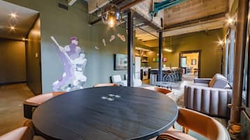 A modern interior with a round table, chairs, and a mural of a baseball player.
