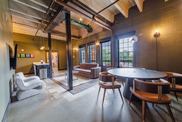 A modern interior with a round table, leather chairs, a sofa, and a bar area.