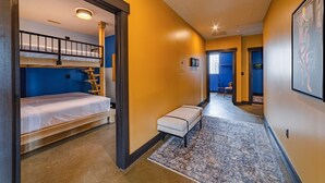A hotel room with a bunk bed, a small seating area, and a hallway leading to another room. - Sleep38 27Beds 10BR Super Stays A12 Up E Crown DD (Louisville)
