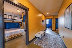 Une chambre d’hôtel avec un lit superposé, un petit coin salon et un couloir menant à une autre chambre.