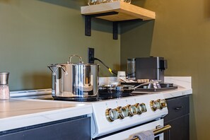 Uma cozinha com fogão, chaleira e máquina de café.