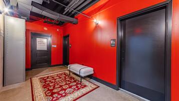 A hallway with a red carpet, a bench, and a door marked 'WOMEN'.