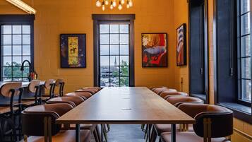 A conference room with a long table and leather chairs, large windows, and artwork on the walls.