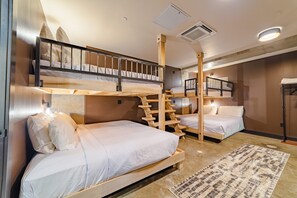 A room with bunk beds, a staircase, and a patterned rug.