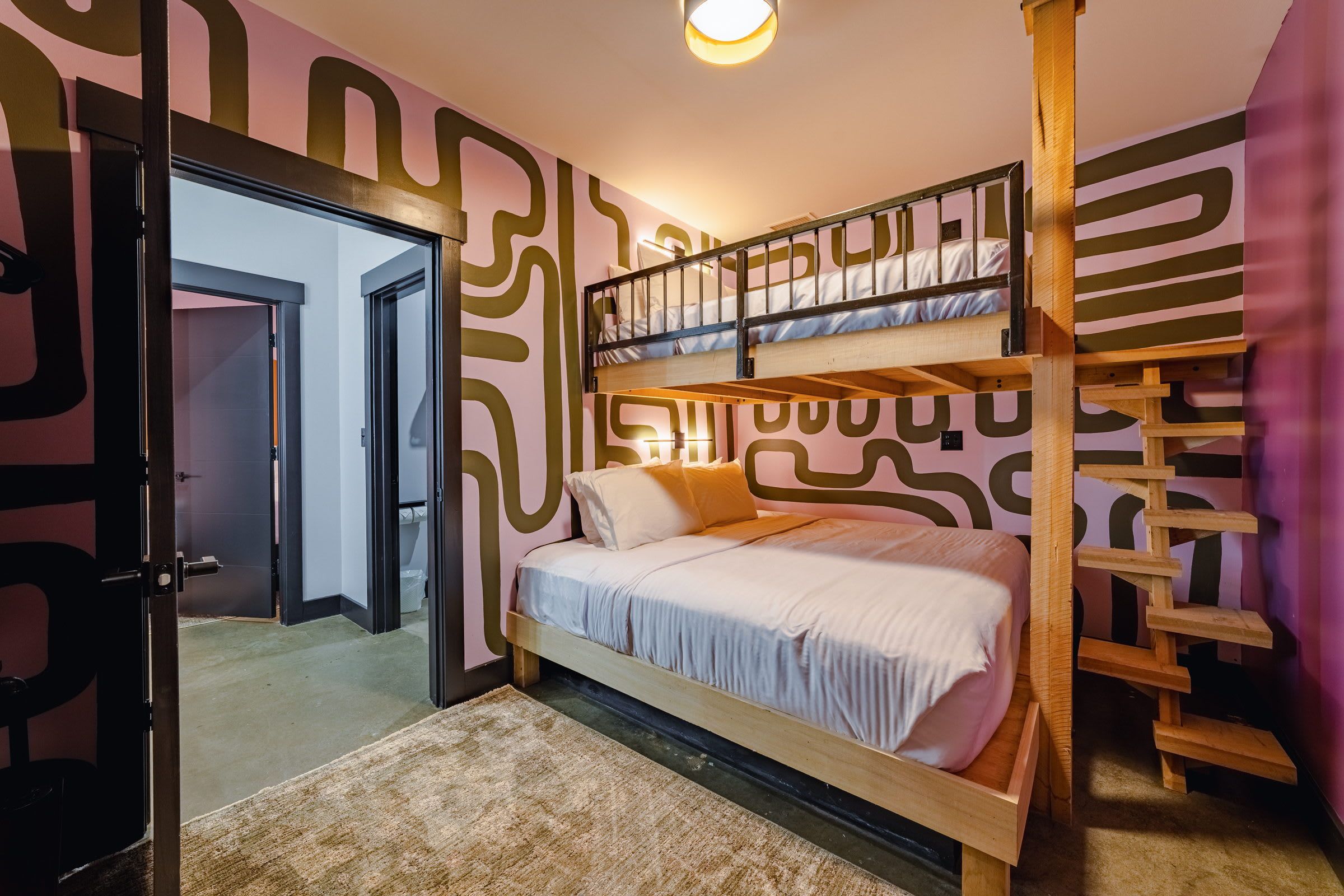 Quarto com beliche, design moderno, porta de acesso a outro espaço e parede estampada.