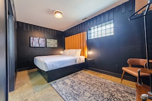 Un dormitorio moderno con una cama, una silla, una alfombra y una obra de arte en la pared.