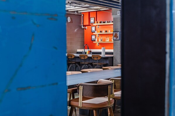 Interior de restaurante con pared de ladrillo, estanterías anaranjadas y sillas de madera.