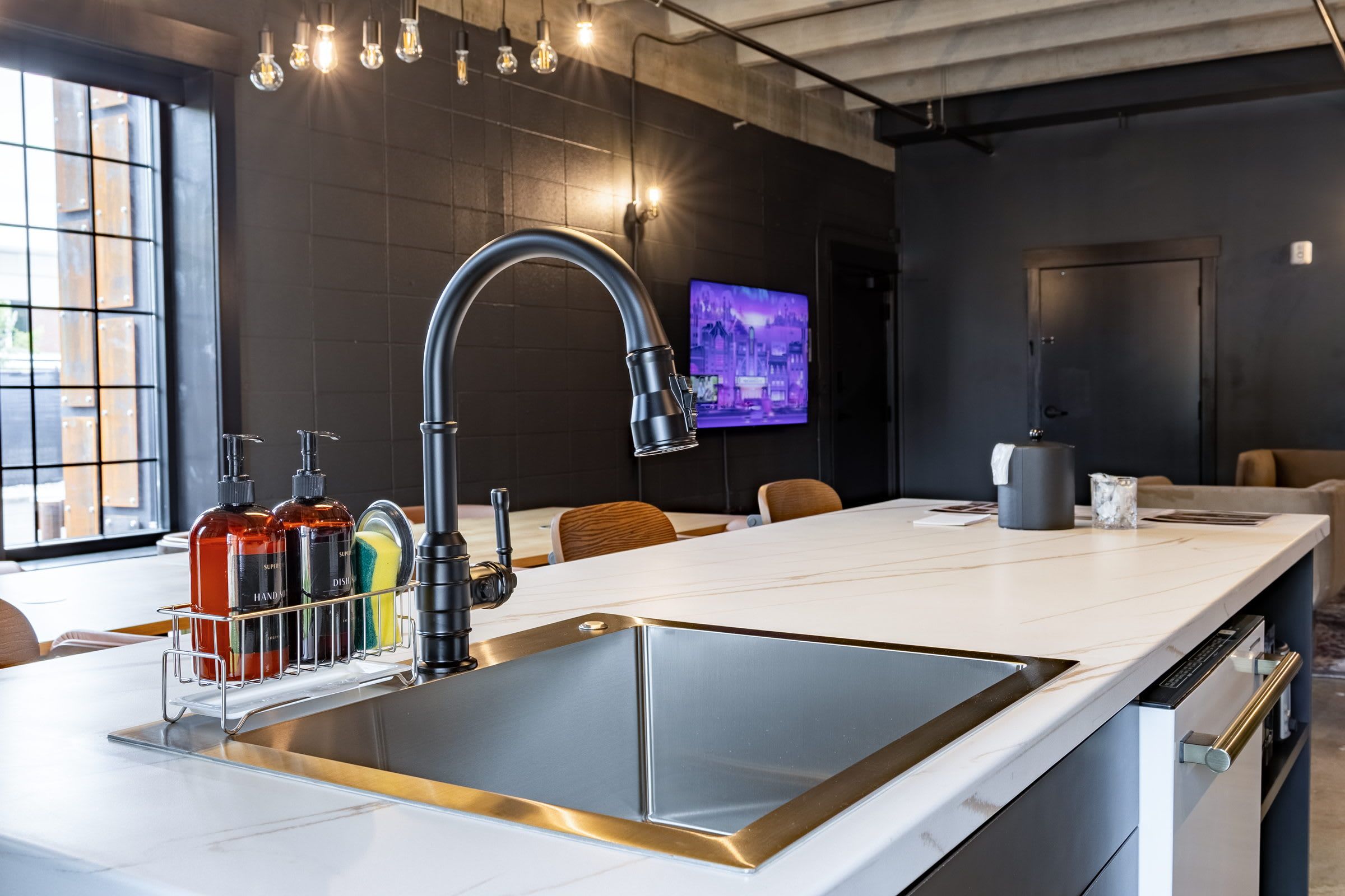 Una cucina moderna con un'isola grande, lavello in acciaio inossidabile e televisore a schermo piatto montato a parete.