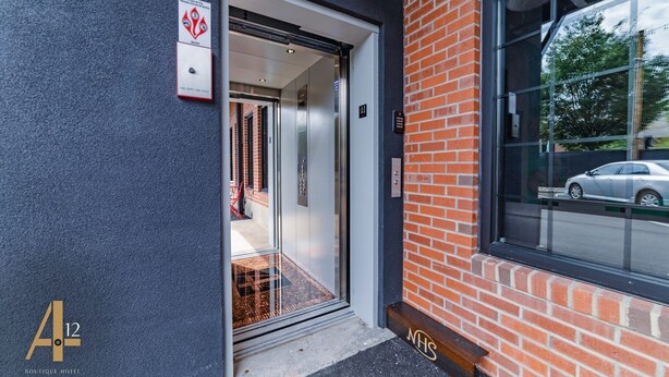 En hotelindgang med en glasdør, en brandalarm og en bil, der kan ses gennem vinduet.