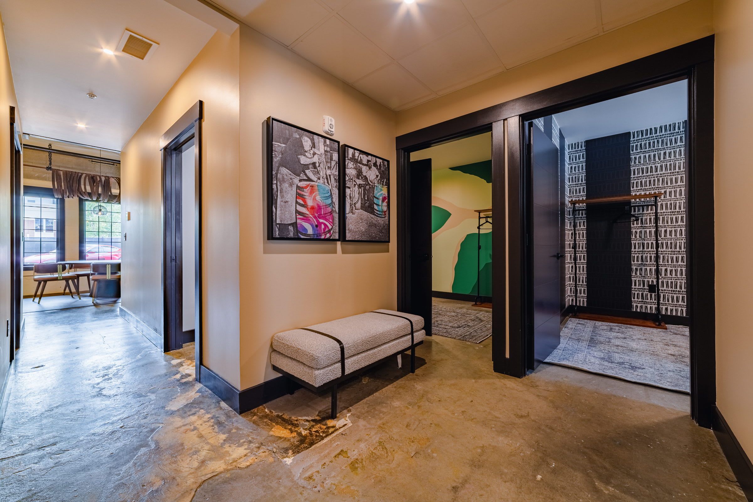 A hallway with a bench, artwork, and a patterned wall.