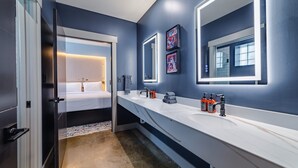 A modern bathroom with a long white countertop, a large mirror, and a bed visible through an open door. - Sleep24 12Beds 8BR Super Stays A12 Low W Stakes Ex (Louisville)