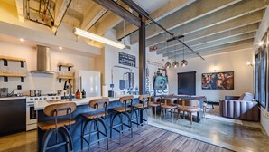 A modern kitchen with a bar area, wooden bar stools, and a dining table with chairs. - Sleep24 12Beds 8BR Super Stays A12 Low W Stakes Ex (Louisville)