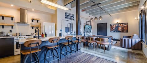 Une cuisine moderne dotée d’un bar, de tabourets de bar en bois et d’une table à manger avec des chaises.