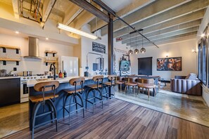 A modern kitchen with a bar area, wooden bar stools, and a dining table with chairs. - Sleep24 12Beds 8BR Super Stays A12 Low W Stakes Ex (Louisville)