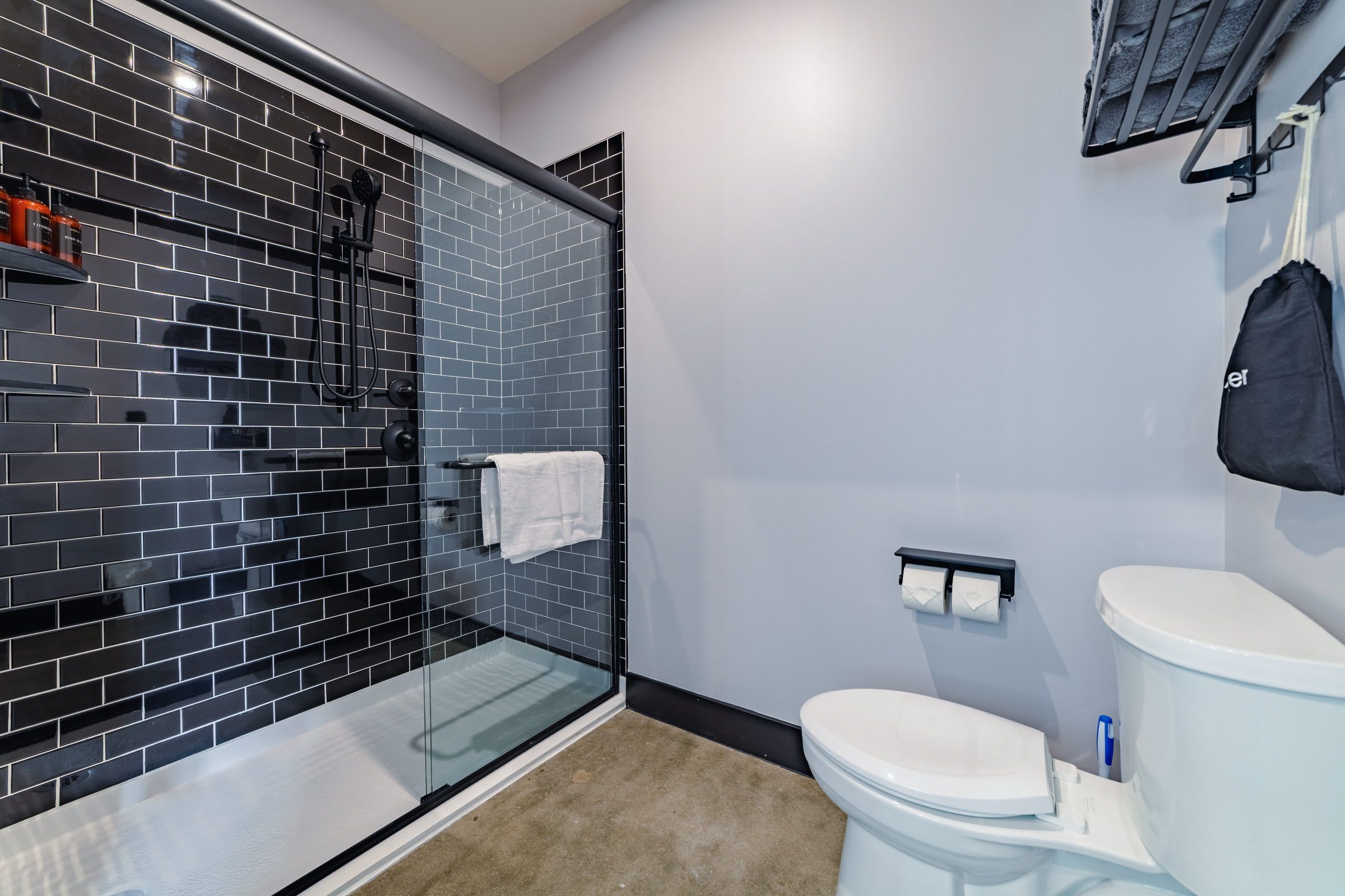 Un baño moderno con ducha envuelta en vidrio, inodoro blanco y un perchero para toallas.
