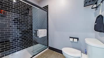 Un baño moderno con ducha envuelta en vidrio, inodoro blanco y un perchero para toallas.