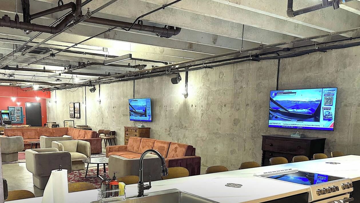 Un'area lounge moderna con divani, un tavolo lungo e un codice QR per visualizzare gli annunci.
