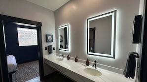 Een moderne badkamer met twee wastafels, grote spiegels en een handdoekhouder.