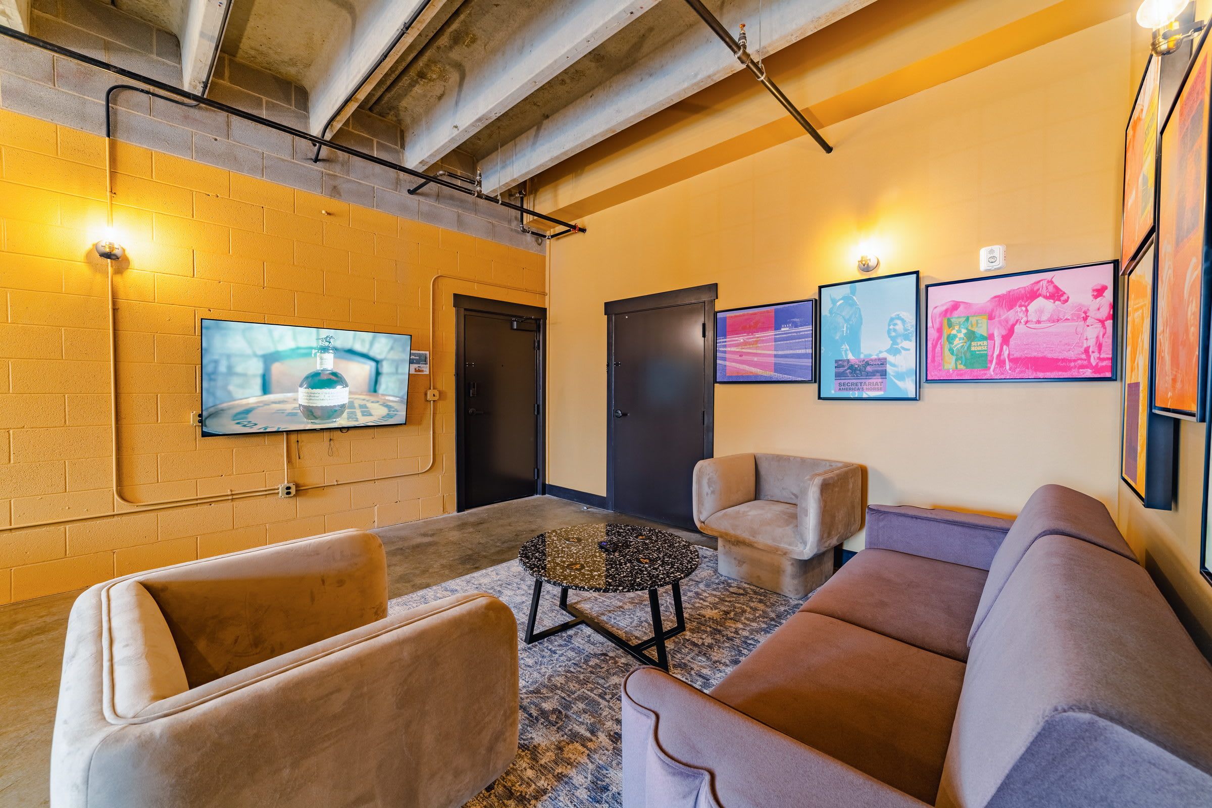 Una hall con un televisore montato a parete, una porta e un'area salotto con due divani e un tavolino.