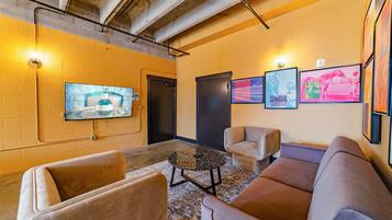 Una hall con un televisore montato a parete, una porta e un'area salotto con due divani e un tavolino.