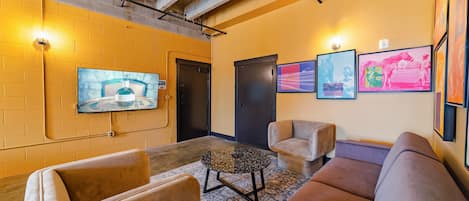 A lobby with a TV mounted on the wall, a door, and a seating area with two sofas and a coffee table.