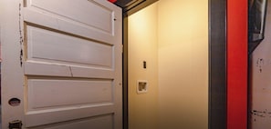 A closed white door with a small rectangular window and a wall-mounted light switch.