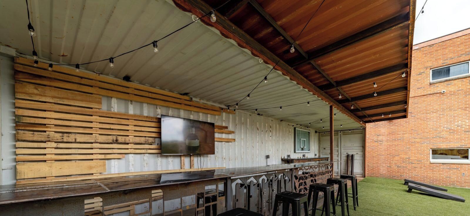 An outdoor bar area with a long counter, wooden slats, and a television mounted on the wall.