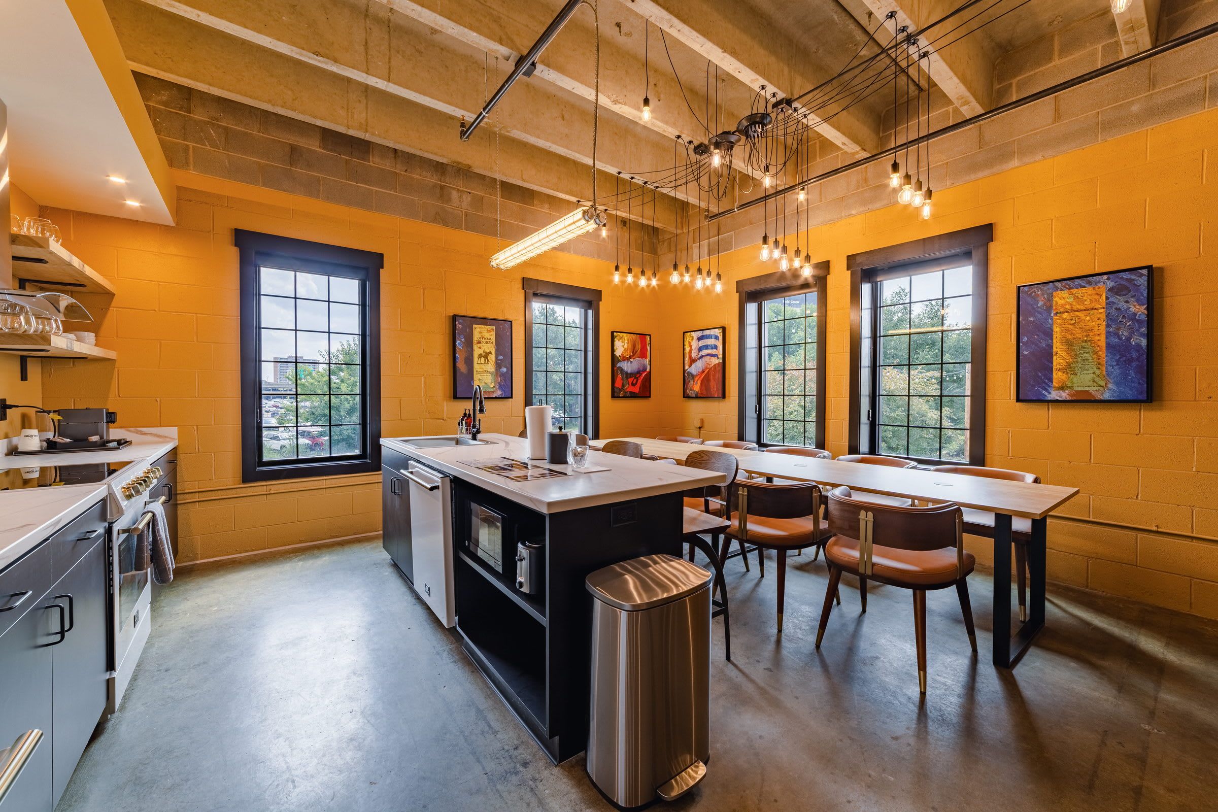 Una cocina moderna con una isla central, comedor con sillas y obras de arte en las paredes.