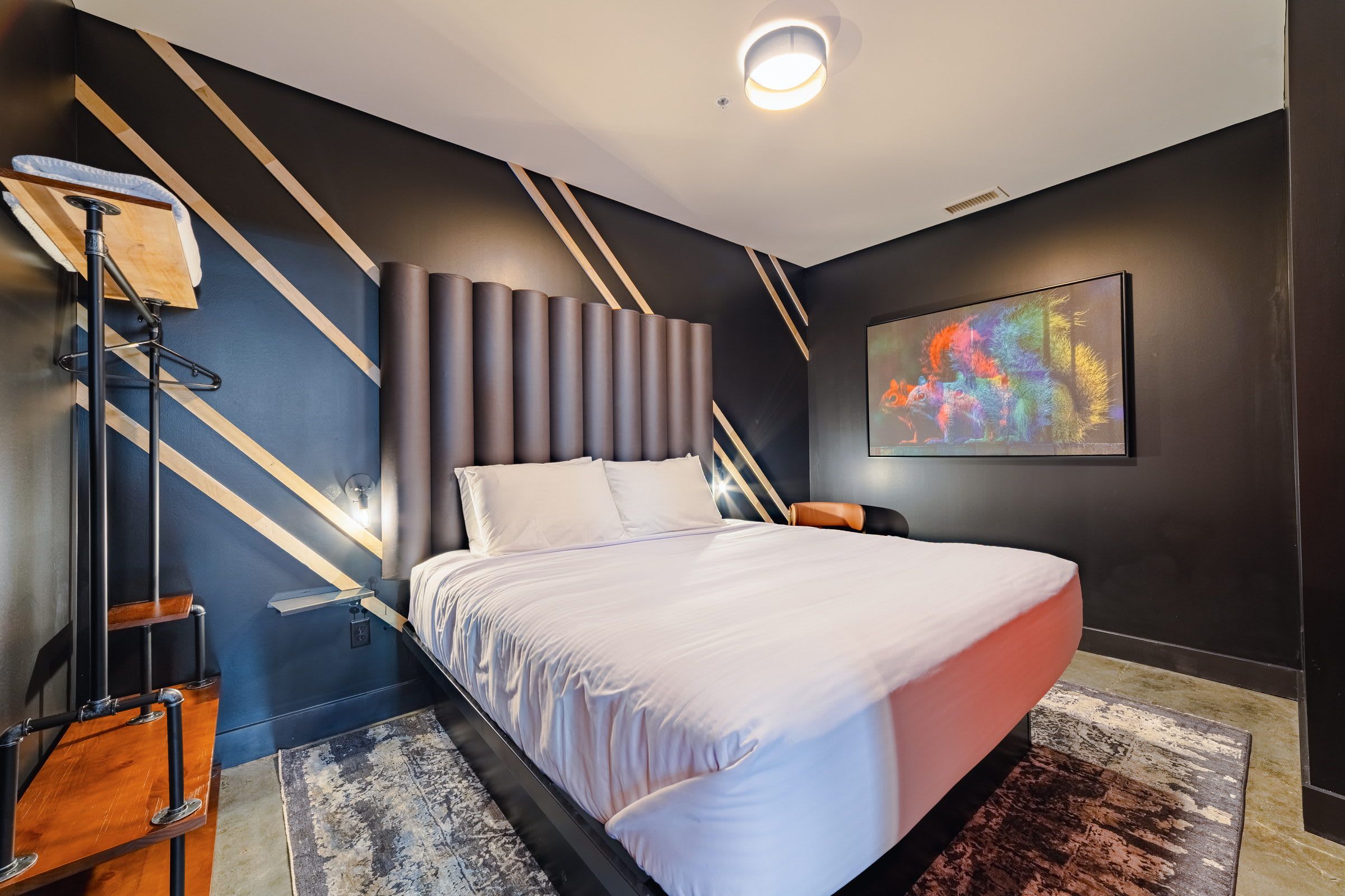 A modern bedroom with a bed, a nightstand, a lamp, and a wall art piece.