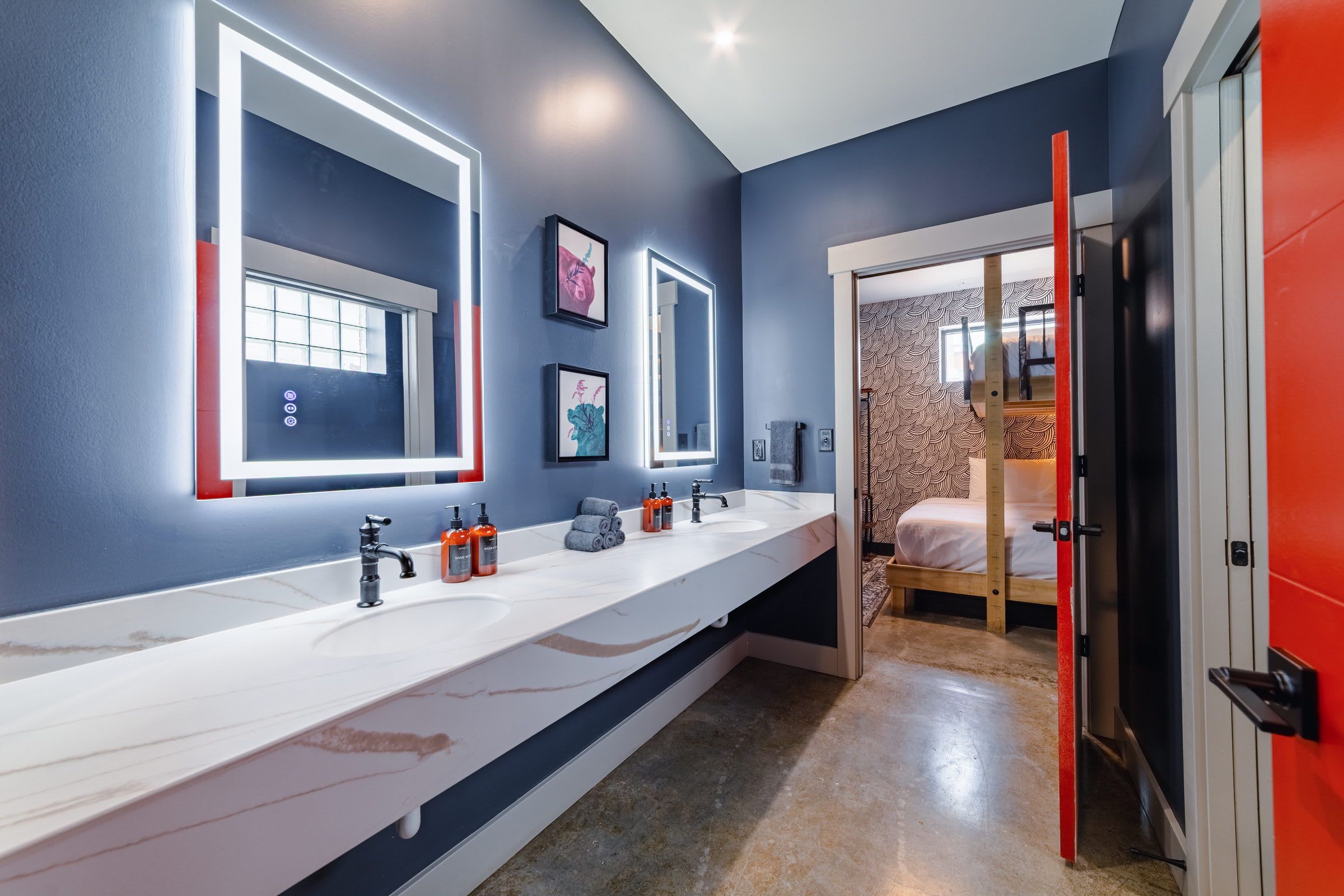 A modern bathroom with a long white countertop, two sinks, and a large mirror.