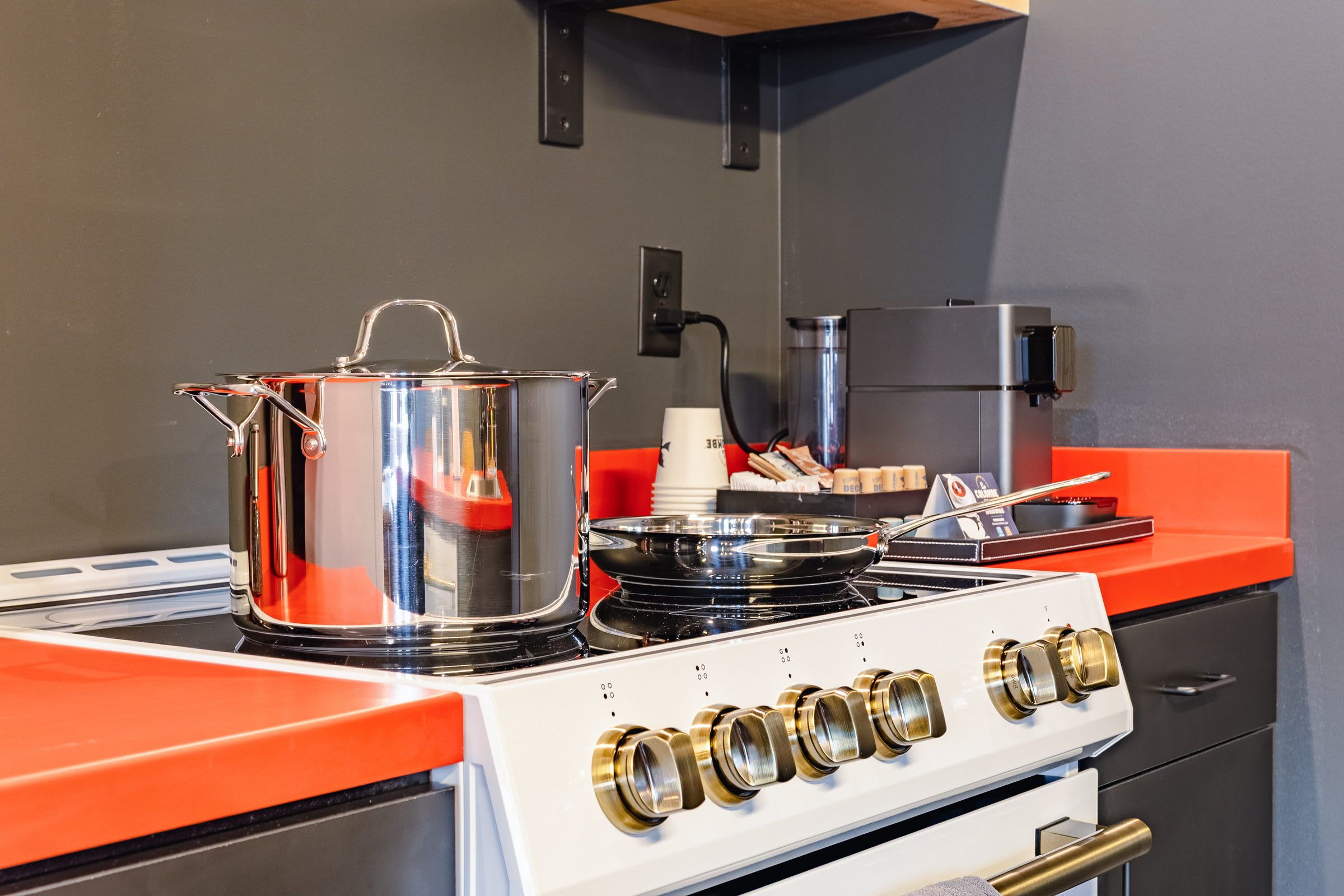 Una cucina con un fornello, pentole e una macchina da caffè.