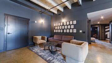 Un intérieur moderne avec un mur foncé, une porte, un canapé, une table basse et un mur décoré de tableaux encadrés.