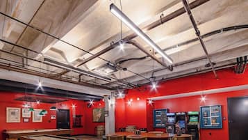 A room with red walls, exposed ceiling pipes, and a pool table.