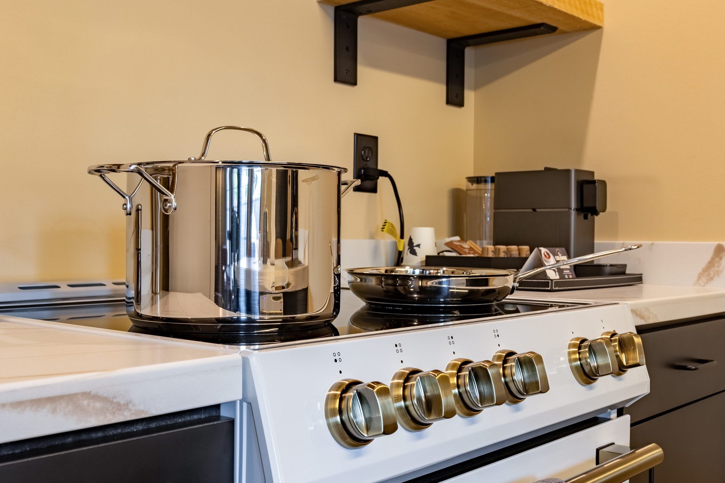 A kitchen with a stove, a pot, and a pan on the counter.