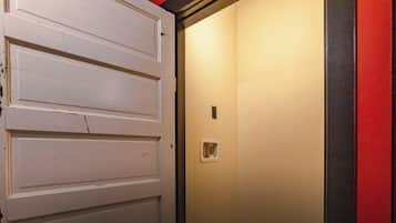 Une porte blanche fermée, dotée d’une petite fenêtre rectangulaire et d’un interrupteur fixé au mur.