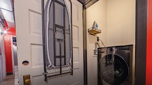 Een wasruimte met een wasmachine en een droogrek.