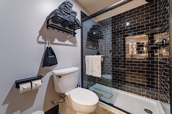 A modern bathroom with a toilet, a towel rack, and a glass shower enclosure.