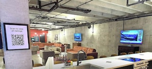 A modern lounge area with sofas, a long table, and a QR code for viewing listings.