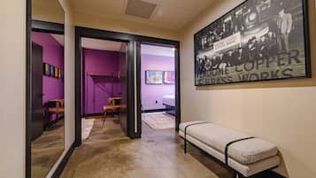 A hallway with a bench, a framed historical photograph, and a door leading to another room.