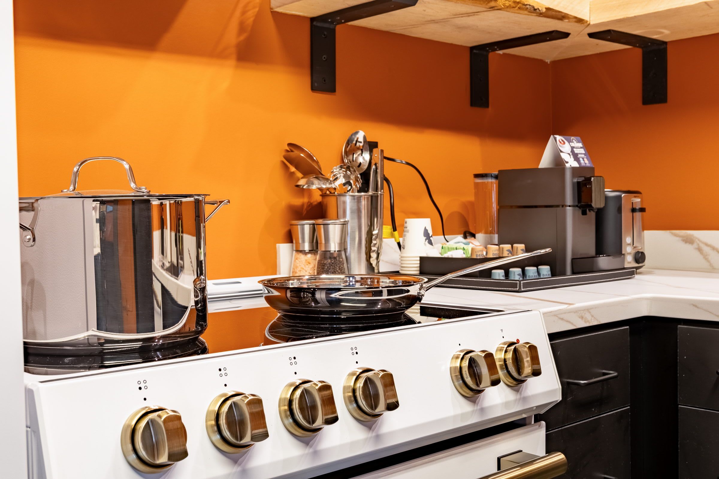 A kitchen with a stove, pots, and a coffee machine.