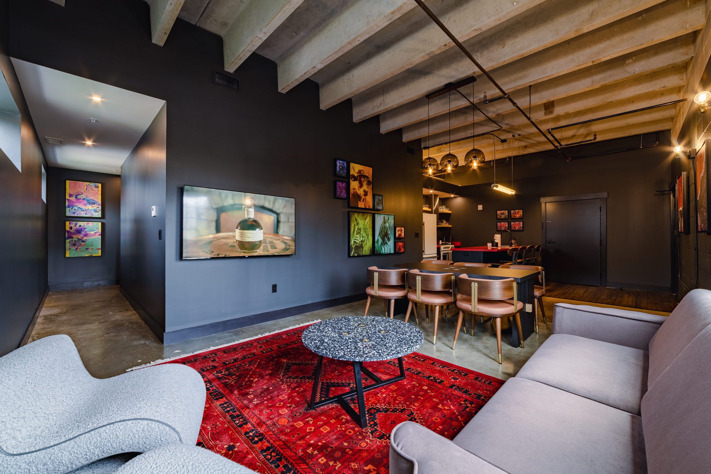 A modern living room with a large TV, artwork on the walls, and a dining area with chairs and a table.