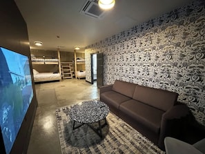A living room with a sofa, a coffee table, a TV, and a patterned wall.