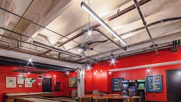 A room with red walls, exposed ceiling pipes, and a pool table.