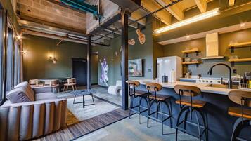 A modern kitchen with bar stools, a dining area with a sofa, and a mural on the wall.