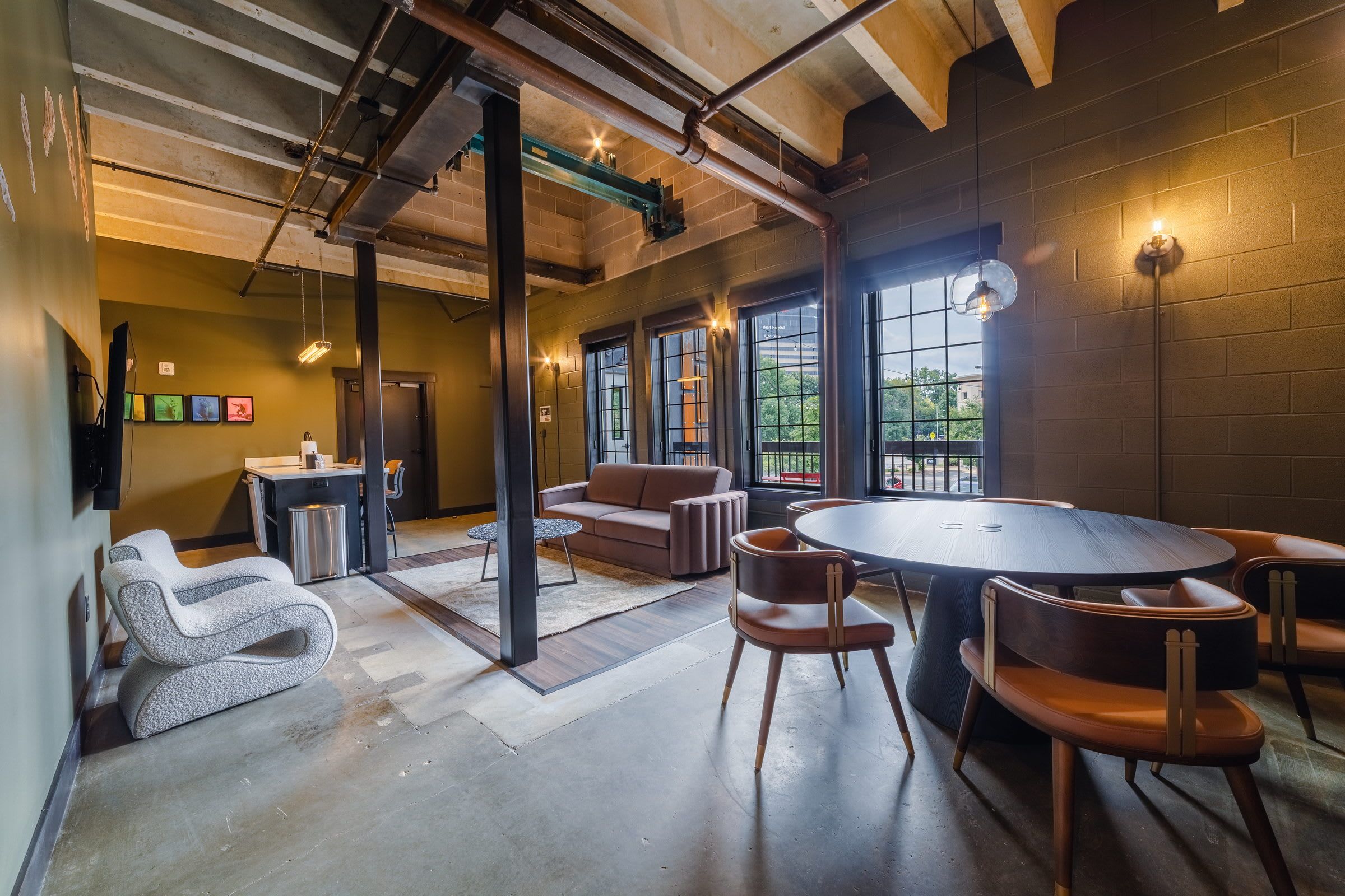 A modern interior with a round table, leather chairs, a sofa, and a bar area.