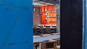 En restaurantindretning med murstensvæg, orange reoler og træstole.